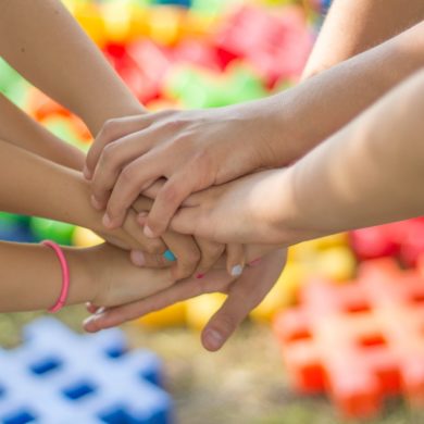 Kinderhände übereinander vereint.